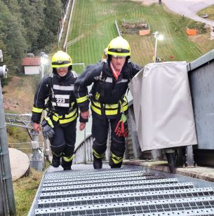 zwei Feuerwehrleute beim besteigen der Treppen neben dem Auslauf der Schanze