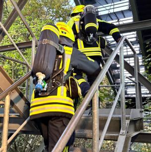 zwei Feuerwehrleute auf der Treppe zum Anlaufturm
